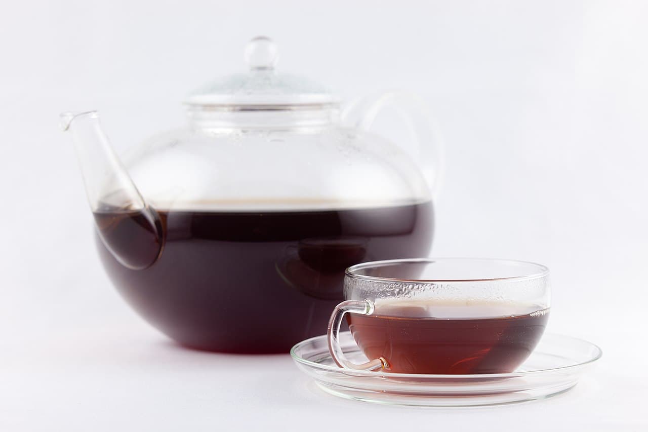 A pressed cake of pu-erh tea beside loose dark leaves